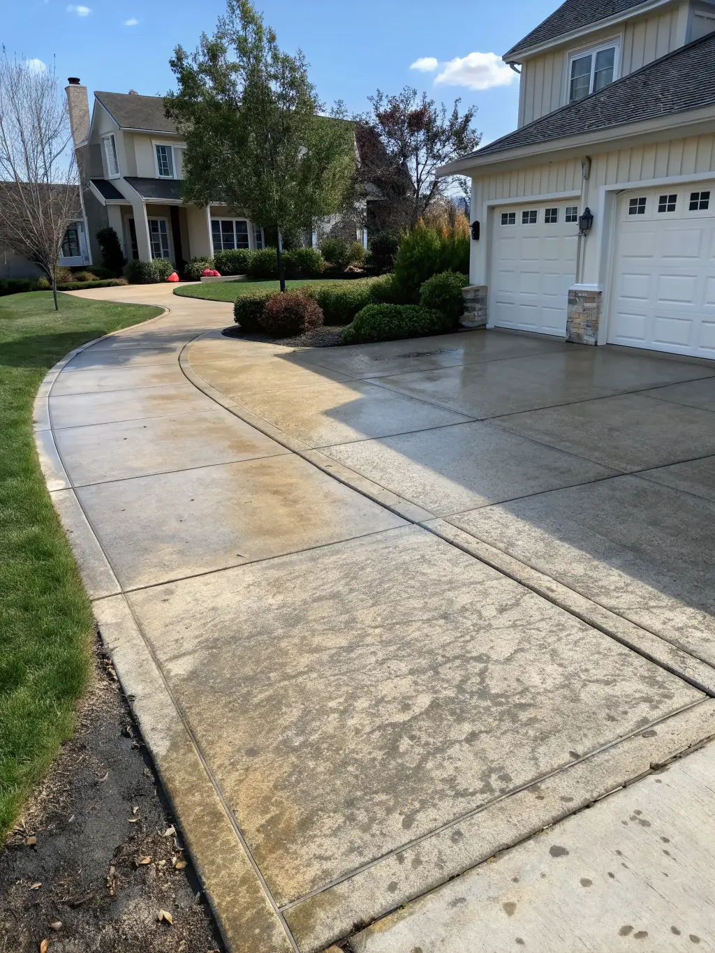 A before-and-after image of a stained driveway transformed into a clean, bright surface, demonstrating the power of TripleJPowerWashing's concrete cleaning.